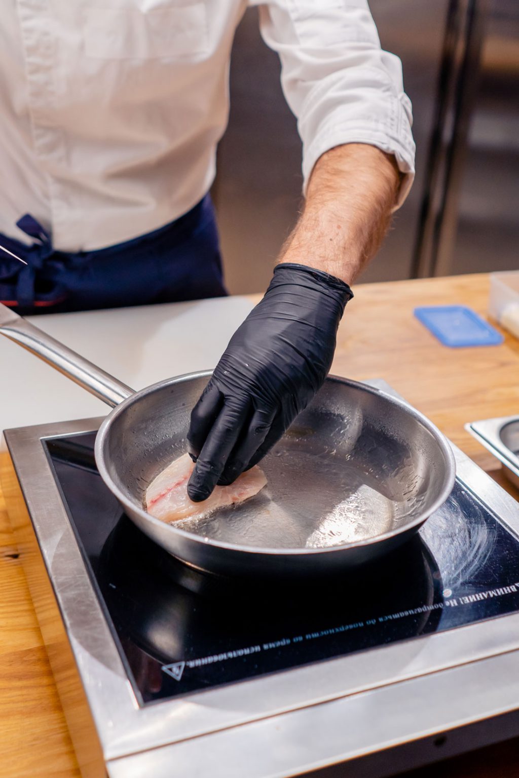 close up of a chef s hands trying to turn fish fil